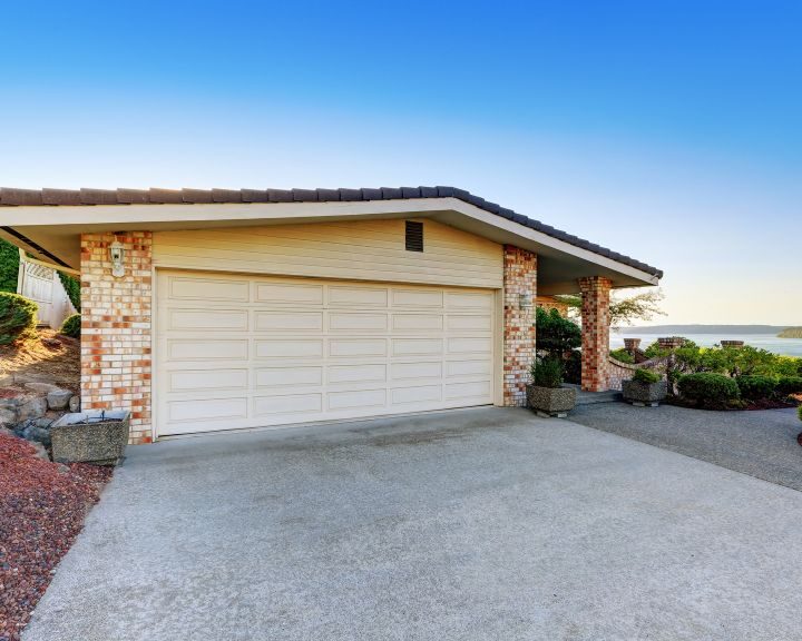 a city home with a concrete driveway and a car parked in front of it.