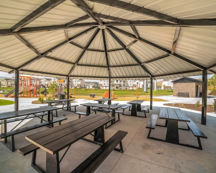 A concrete patio picnic area with picnic tables and benches in the city.