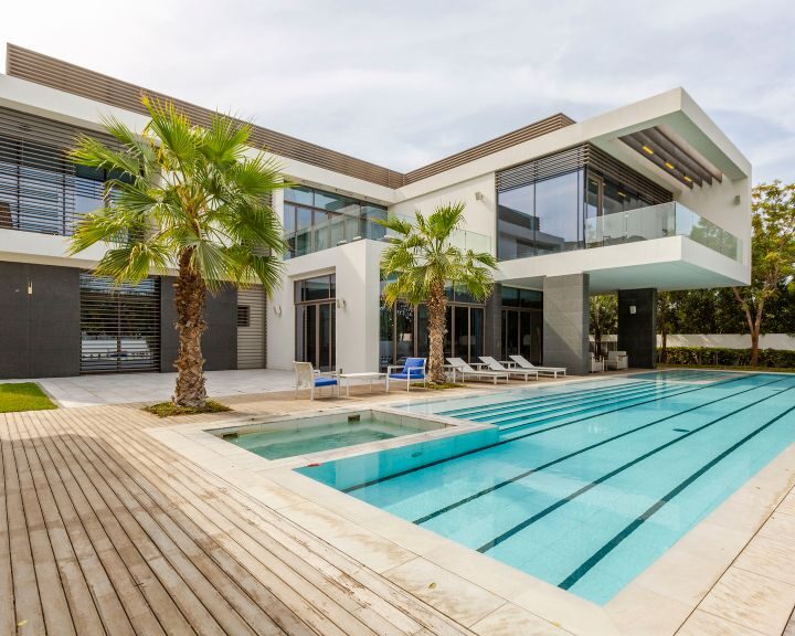 A city house with a concrete pool deck in front of it.