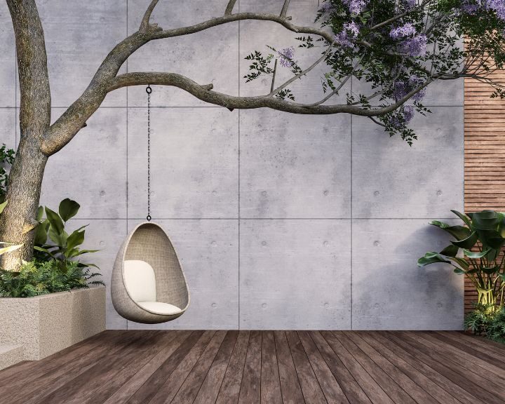 A swing chair and tree in a room with concrete walls.