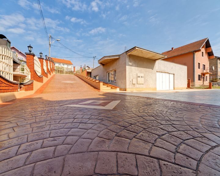 A stamped concrete city street with houses in the background.
