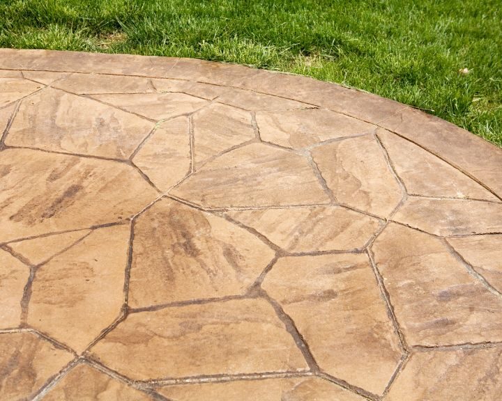 A stamped concrete patio with grass in the background.